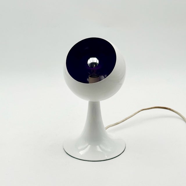 A sculptural table lamp featuring an elegant tulip-shaped base and a distinctive spherical shade with a striking purple...