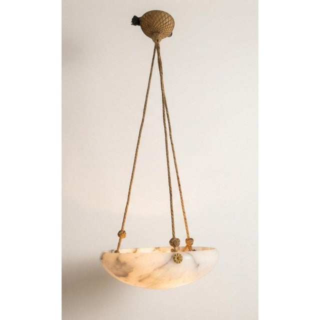 A sculptural Swedish hanging pendant lamp from the 1940s, featuring a hand-carved alabaster shade with beautiful natural...