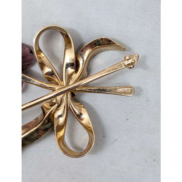 1950s goldtone two molded purple glass flowers with faux-pearl dangles centers with a bow around the stems brooch with...