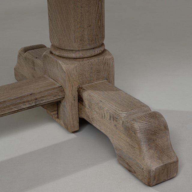 This 20th Century French oak trestle dining table features a bold, architectural silhouette rooted in traditional...