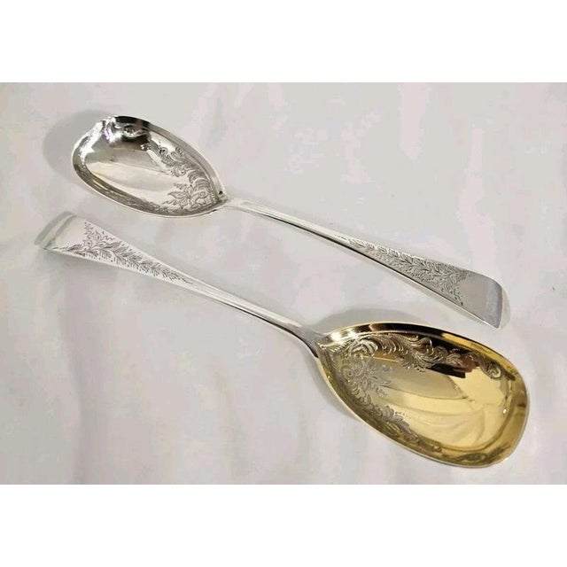 A fine pair of Edwardian sterling silver and gilt serving spoons dating to 1905, beautifully designed for serving berries,...