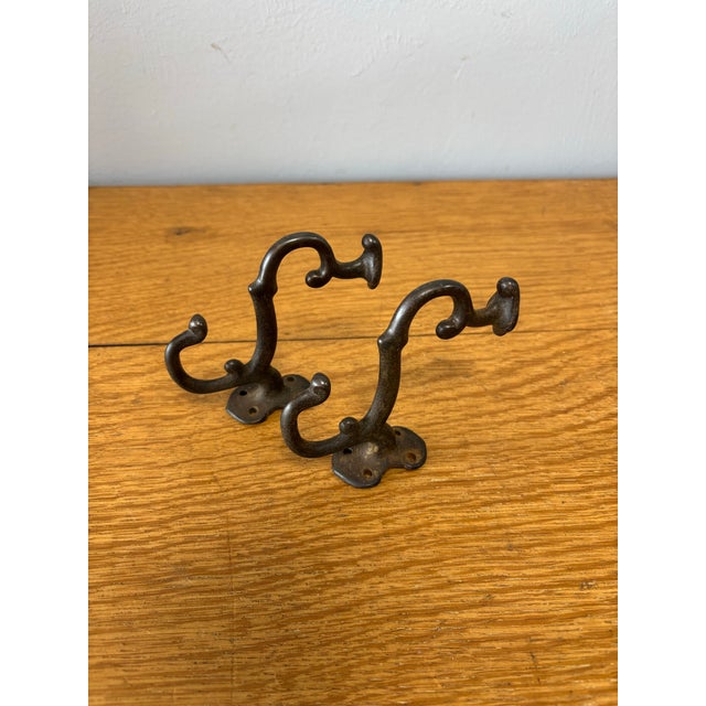 A handsome pair of antique cast metal wall-mounted coat and hat hooks, full of the quiet character and utility that...