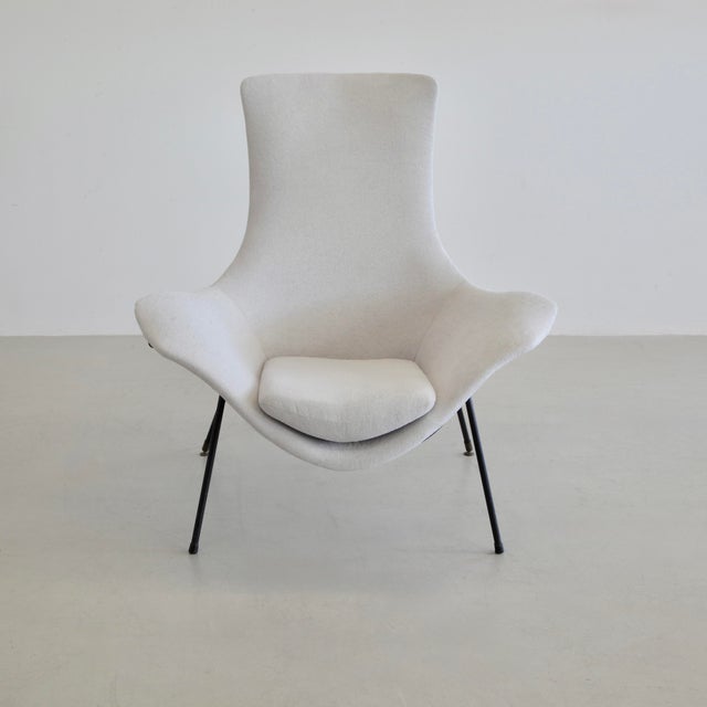The 'Cosmos' lounge chair with a painted black tubular metal frame and a high-backed lounge seat, upholstered in a soft...