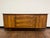 Mid-Century Modern credenza or dresser with dual side cabinets with sculpted doors, three dovetail drawers with pulls...