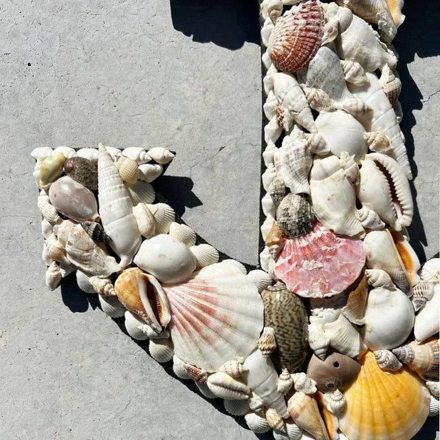 A natural hand-crafted sea shell encrusted anchor wall hanging. Created from wood, this piece is in the shape of a boat...