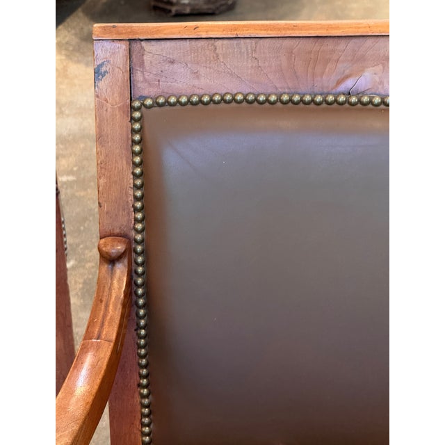 A handsome pair of French fauteuils with warm wood frames and a strong, architectural presence. The tall rectangular backs...
