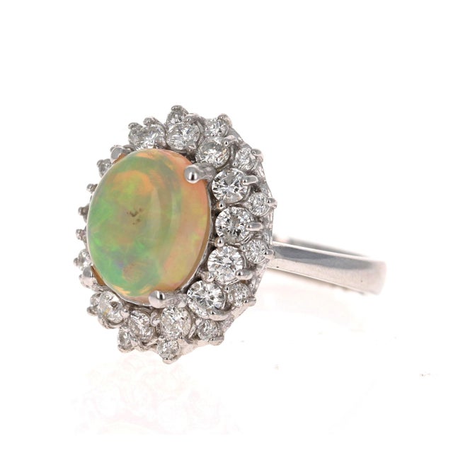 This ring has a gorgeous Oval Cut Opal in the center that weighs 2.72 Carats and has a clusterof 28 Round Cut Diamonds...