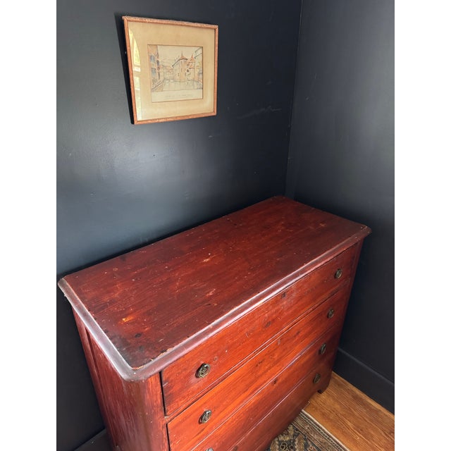 Oxblood painted pine chest of drawers with lovely patina and charming antique metal pulls. Drawers feature pin and cove...