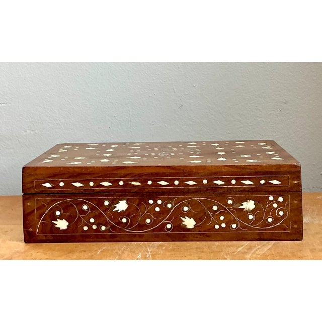 Crafted from rich, warmly patinated wood, this mid-20th-century rectangular decorative box highlights artisanal marquetry...