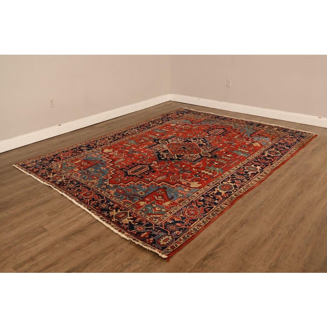 High Quality Antique Heriz Hand Tied Oriental Rug Featuring A Bold Geometric Medallion Set Within A Deep Red Field. The...