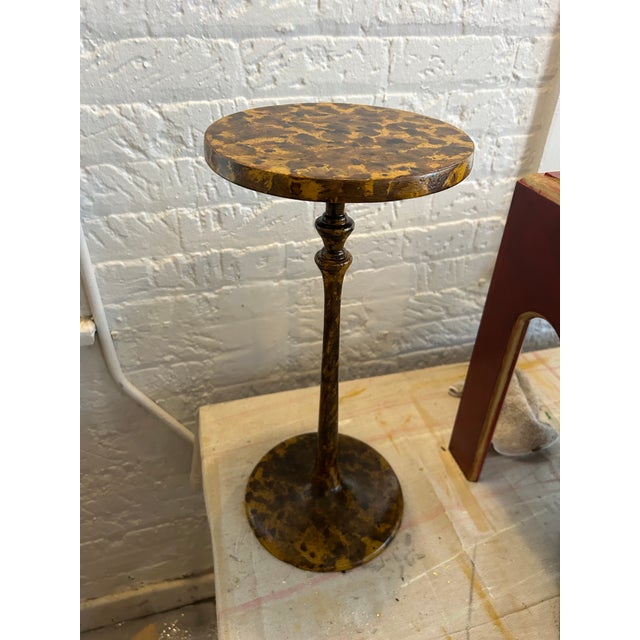 Drink table is made of metal and painted in a faux tortoise shell finish.