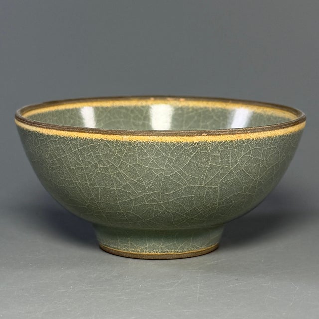 This antique Chinese Longquan celadon bowl has a classic rounded shape. The surface is covered with natural crackled glaze...