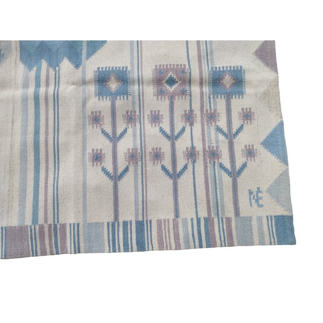 Hand-woven wool tapestry rug in shades of blue, featuring stylized birds and flowers (organic-geometric style). The...