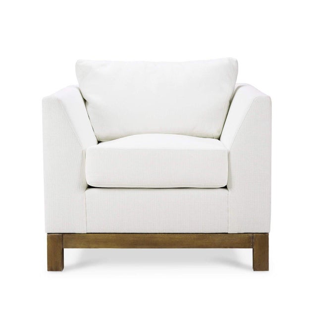 This exquisite armchair features a sleek, angular frame upholstered in premium arctic white performance fabric, providing...