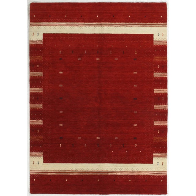 Vintage Hand-knotted Gabbeh rug featuring a rich red field framed by contrasting ivory borders with subtle geometric and...
