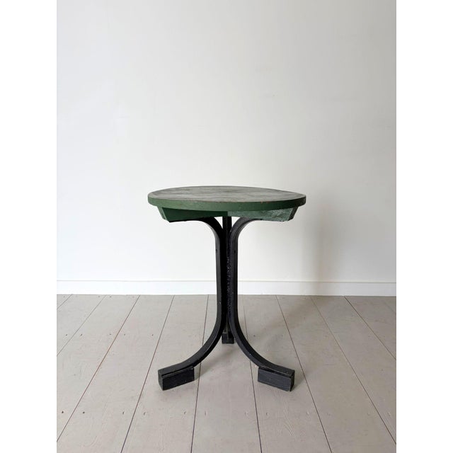 An unusual French wooden side table with splayed iron legs culminating in block feet. The circular timber top has been...