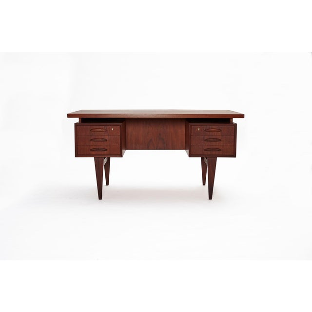 Solid teak legs with a teak-veneered top. The desk is in very good vintage condition and has been completely restored. All...