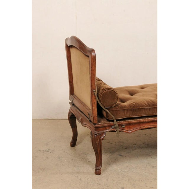 A French carved-wood and upholstered reclining sofa-bench from the 18th century. This antique chaise bench from France is...