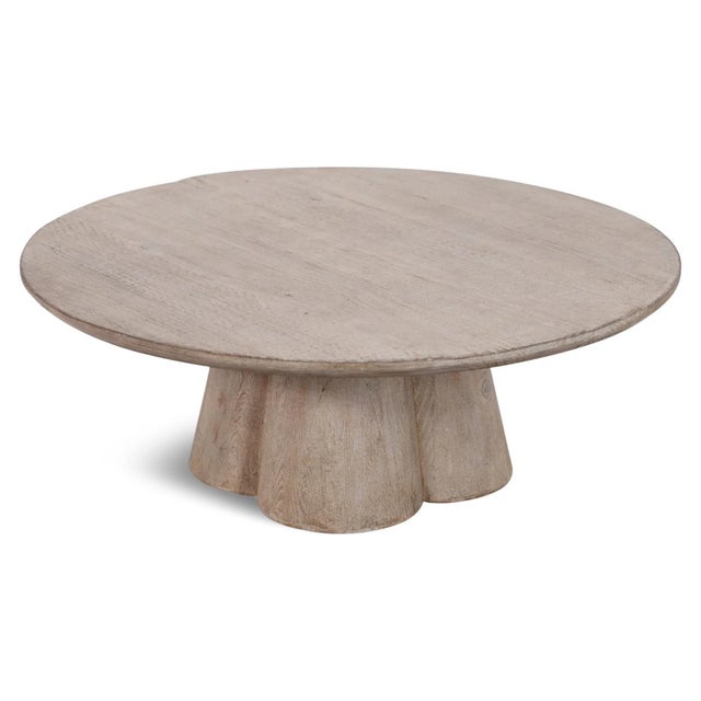 Modern sculptural round coffee table crafted from solid salvaged pine wood with a light washed finish that highlights the...