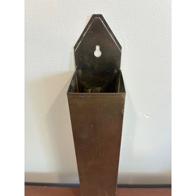 Vintage brass tone wall-mounted match holder featuring a sleek tapered silhouette and warm aged patina. This functional...