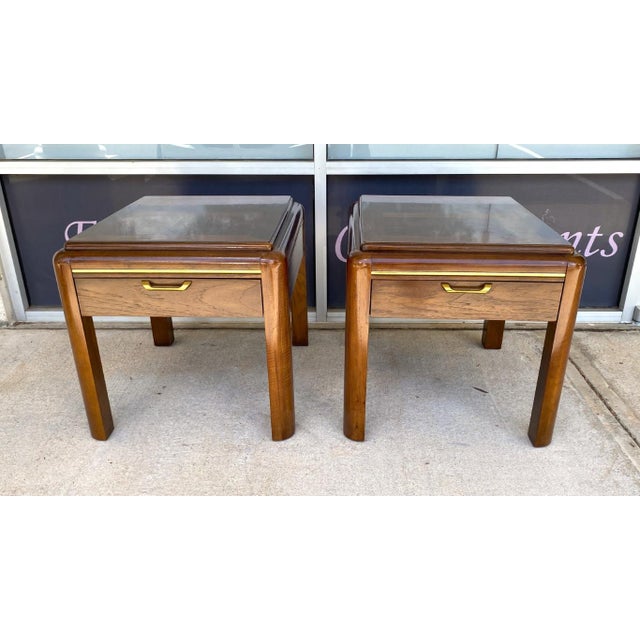 This pair of vintage Thomasville Mystique end tables features richly figured burl-style tops, brass campaign-style...