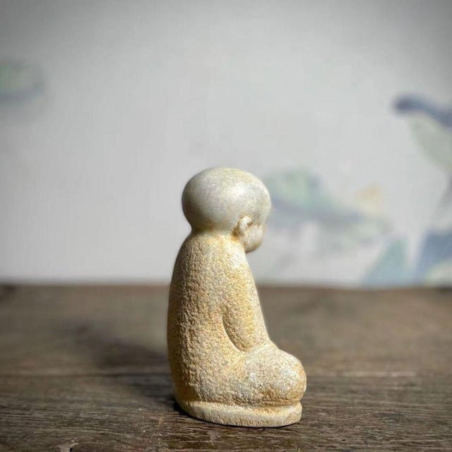 This elegant Chinese sculpture depicts a young monk seated in a calm and contemplative pose, finely carved from white...