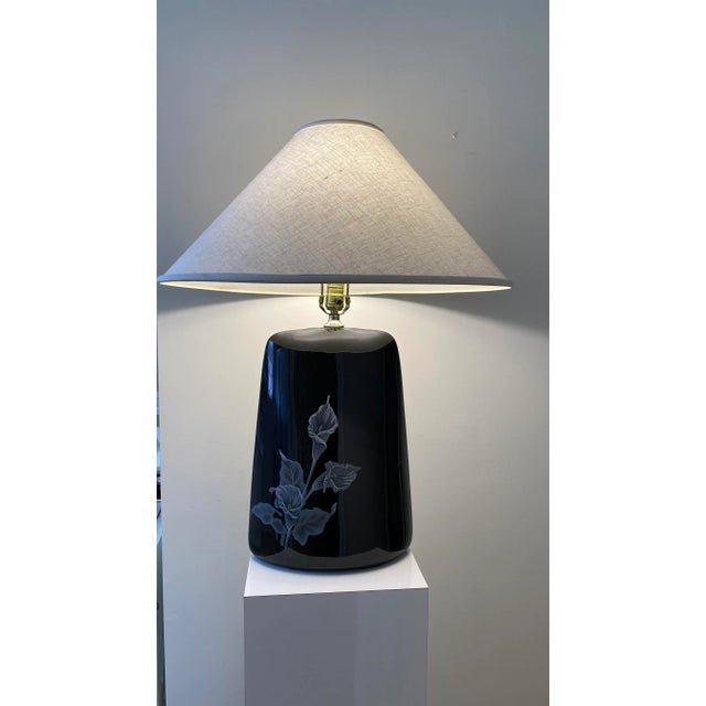 Beautiful, tall and elegant black ceramic Art Deco table lamp with shade. Featuring white lilies Cascading down the front...