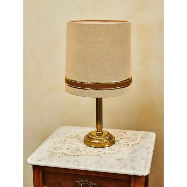 Elegant vintage lamps with a brass patinated leg and a fabric shade in a beige shade. The classic design with subtle gold...
