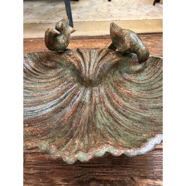 Beautiful verdigris iron birdbath having a shell form basin and adorned with darling birds on the edge.