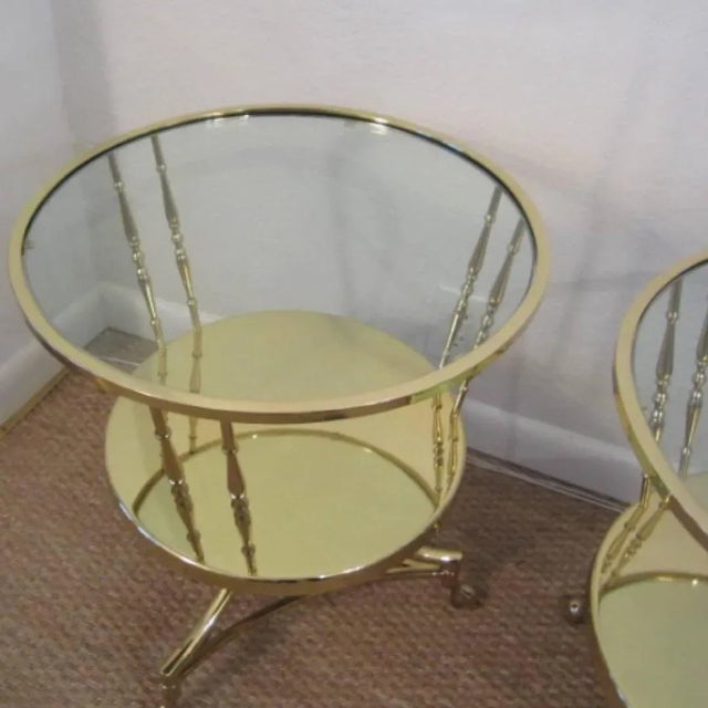 Solid brass two-tier round side tables with glass tops. The glass tops are recessed and flush with the frame providing a...