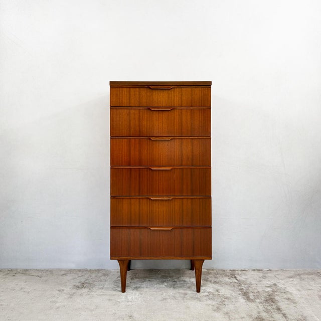 A tall, narrow chest of six drawers by Austinsuite, finished in teak veneer with a fine straight grain. It's a good fit...