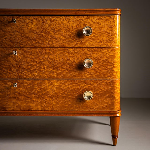 Art Deco chest of drawers featuring three drawers fitted with round brass knobs and working locks. The piece stands on...