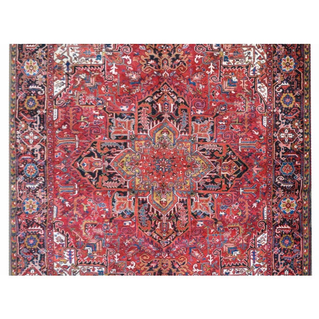 A wonderful mid-20th century Persian Heriz rug with a traditional large-scale stylized floral medallion woven in myriad...