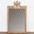 This striking mirror is crowned by a carved Grecian urn and garland. Burnished gold and brick red/brown accent the...