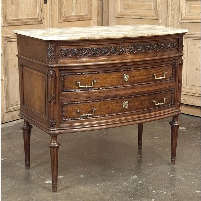 19th Century French Louis XVI Walnut Commode was hand-crafted from select French walnut, and features timeless...