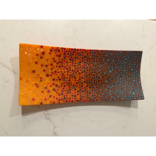 15 1/4 L x 6 3/4 W one-of-a-kind glass platter from artist Robin Kittleson, featuring an ombre orange color with blue and...