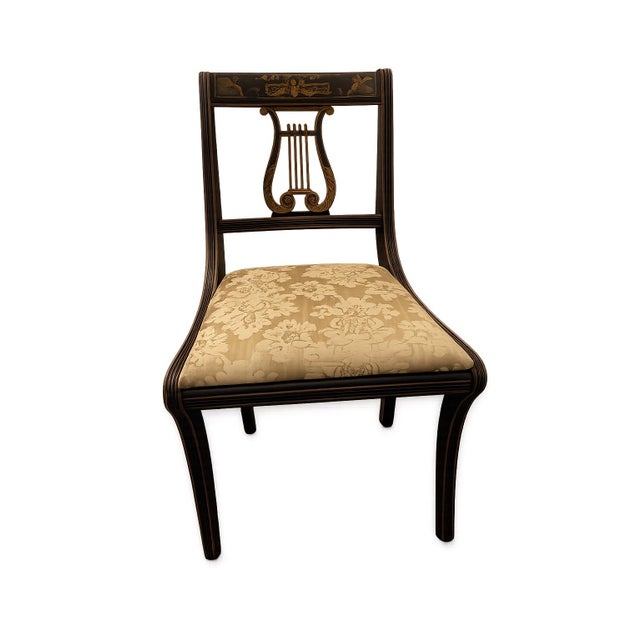 Elegant set of six Regency-style dining chairs featuring an ebonized wood finish with hand-painted parcel-gilt decoration....