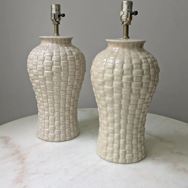 A pair of 1980's vintage ceramic ginger jar lamps. The lamps feature basket-weave relief and speckle glaze finish....