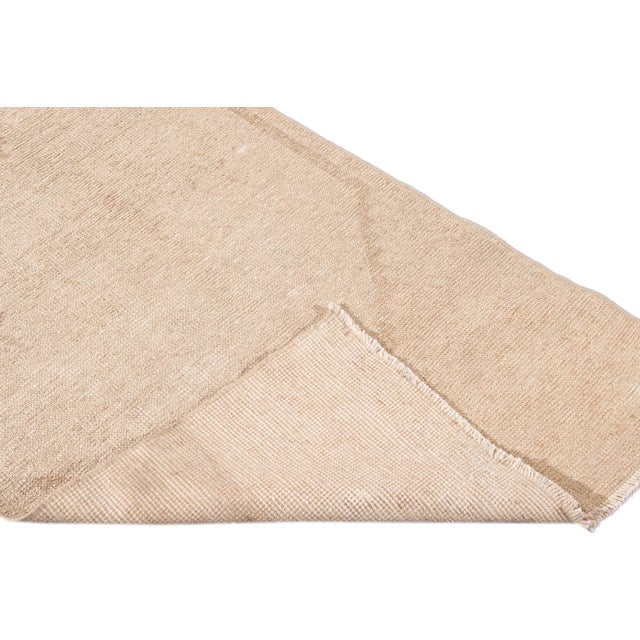 Beautiful vintage Turkish hand knotted wool rug with a beige field. This rug has brown accents in a gorgeous all-over...