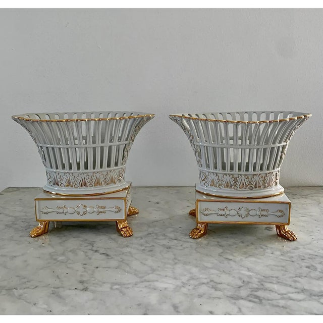 A refined pair of reticulated porcelain baskets, executed in a neoclassical idiom with delicate openwork and restrained...