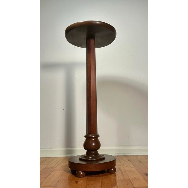 This is a vintage, decorative, Mid Century solid walnut plant stand or pedestal table. Features a simple flat circular...