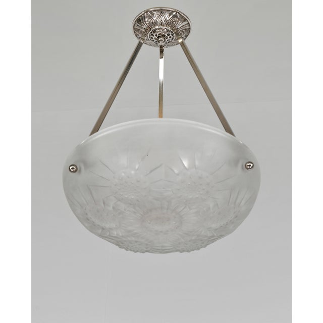 Noverdy A French 1930s art deco pendant light in nickel plated solid brass. It holds a bowl in clear frosted molded-...