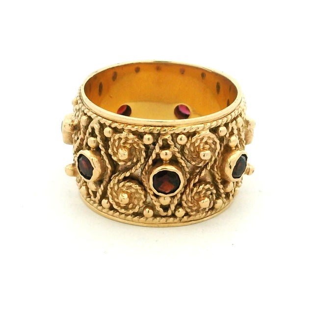A substantial vintage 14K yellow gold and ruby wide band ring, circa 1970, designed in the Etruscan Revival tradition. The...