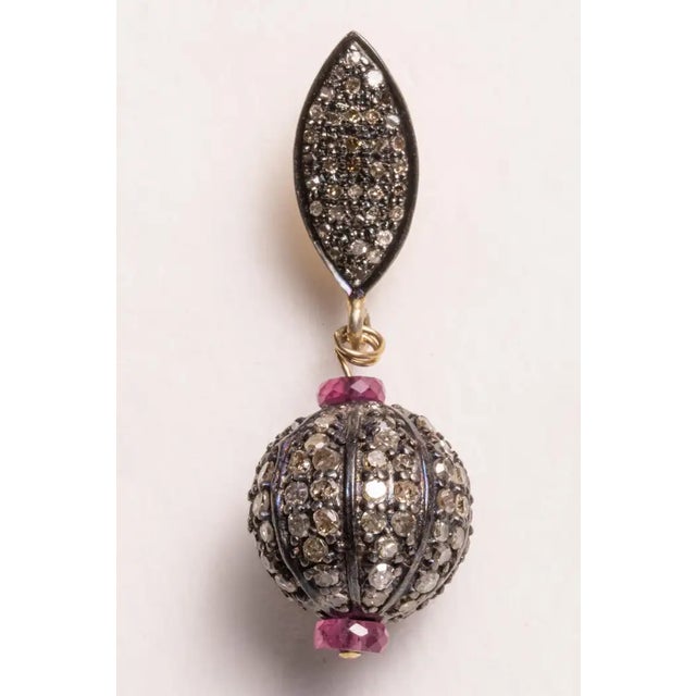 Pave`-set diamond balls and earring posts with round, brilliant cut diamonds with faceted pink rubies. Set in sterling...