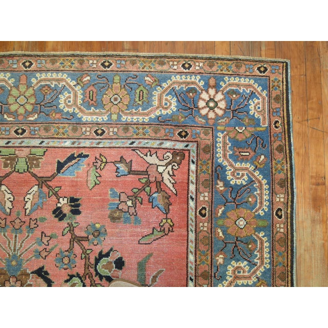 20th century Persian Malayer rug featuring a paradise floral motif on a pink ground surrounded by a soft blue border,...