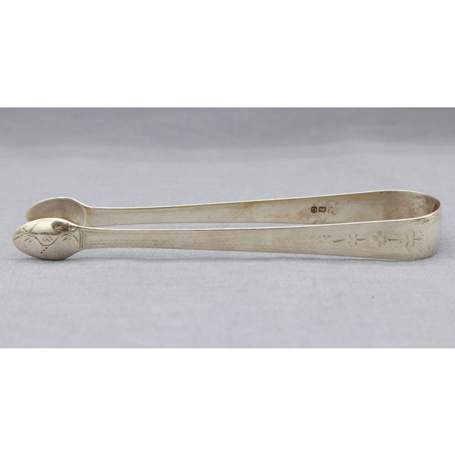 Sterling silver sugar tongs by Samuel Hougham, London, 1802. Neoclassical bright-cut decoration. Period monogram "CST"....