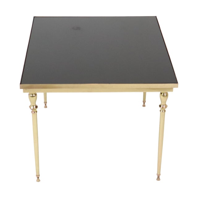 A high-quality vintage french coffee or side table featuring a brass base and a black smoked-glass top; designed entirely...