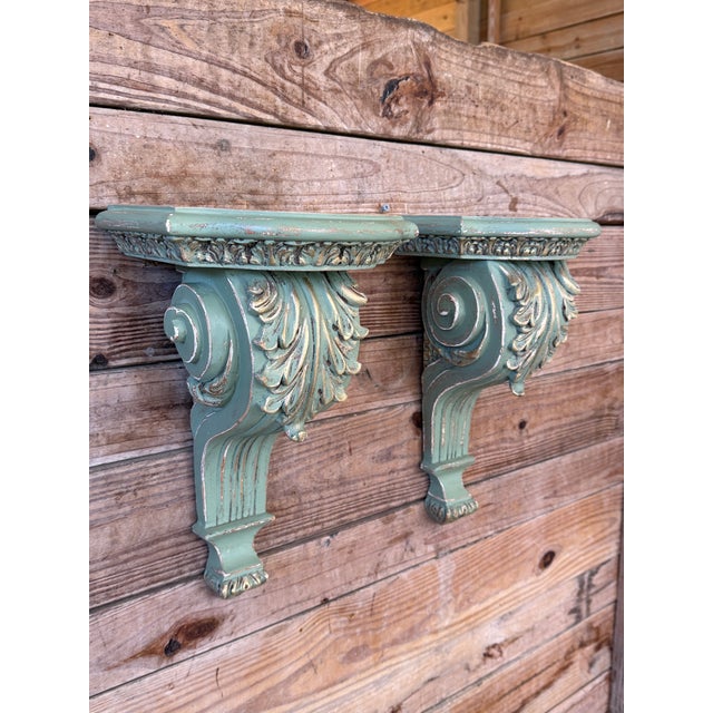 A striking pair of carved wall bracket shelves featuring classical acanthus leaf and scroll detailing in a beautifully...
