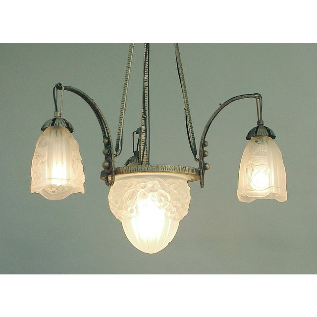 Offering a classic four-light French Art Deco wrought iron chandelier with unsigned but very high quality glass, in the...