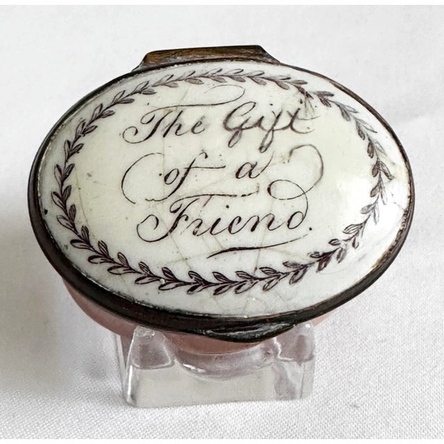 An oval Battersea Bilston English Enamel Love Motto Patch Box. The top reads “The Gift of a Friend” with a decorative...